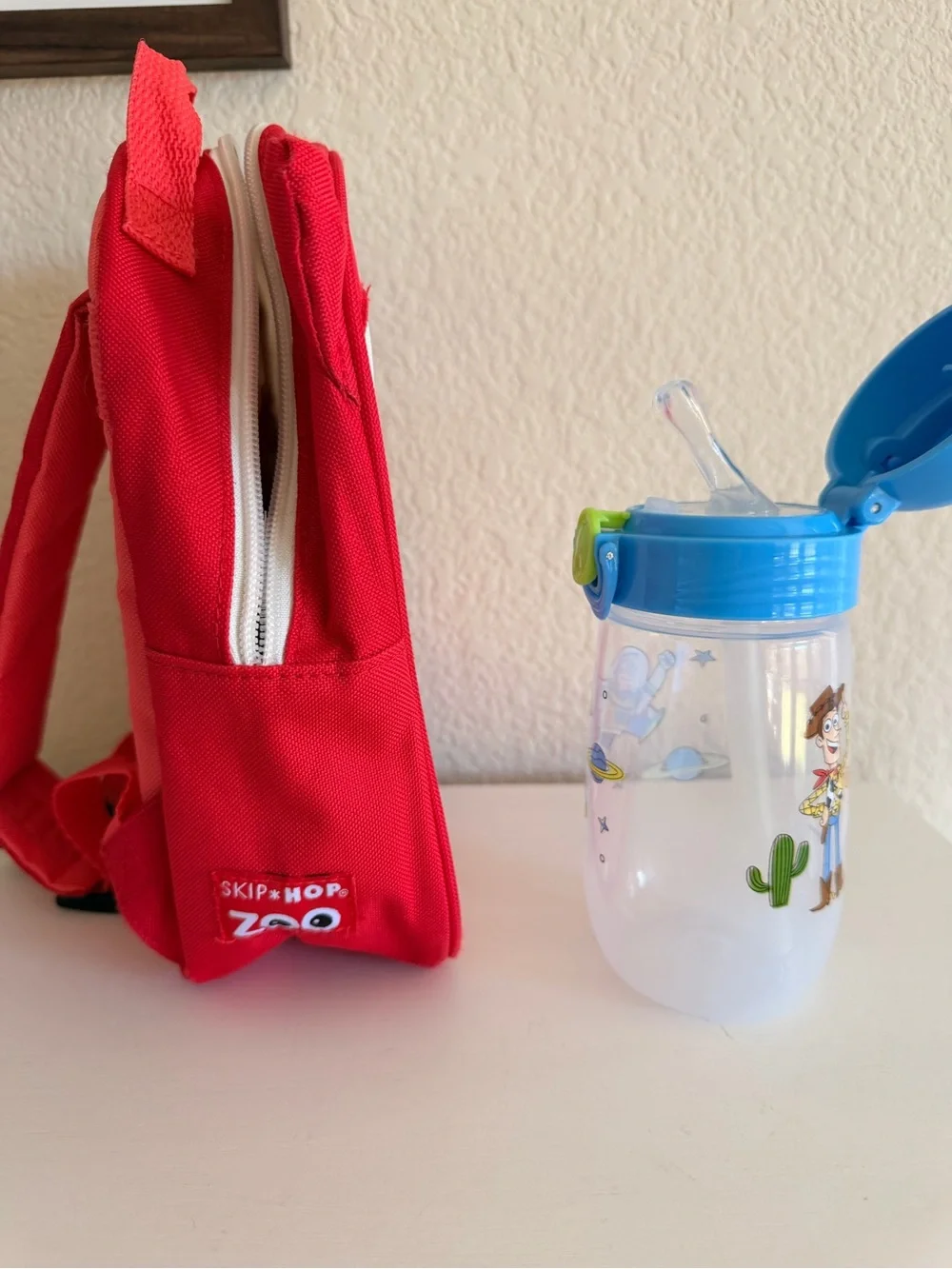 Skip Hop Zoo Mini Backpack with Blue and Toy Story Sippy Cup.